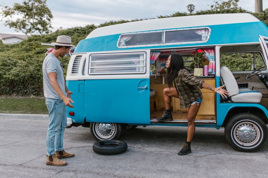 pexels-photo-8231098 A couple is seen arguing near a vintage campervan with a flat tire on a city street.